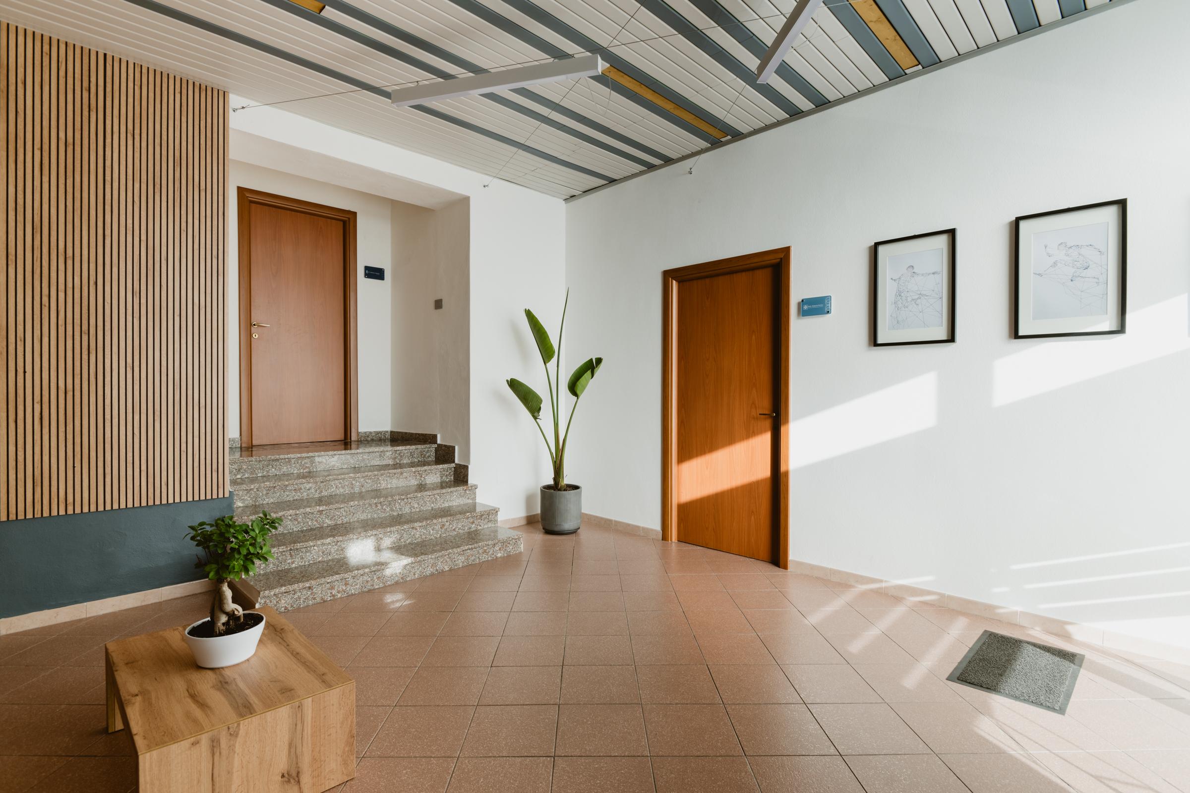 Studio F.N., ingresso con scala, porte in legno e parete a listelli