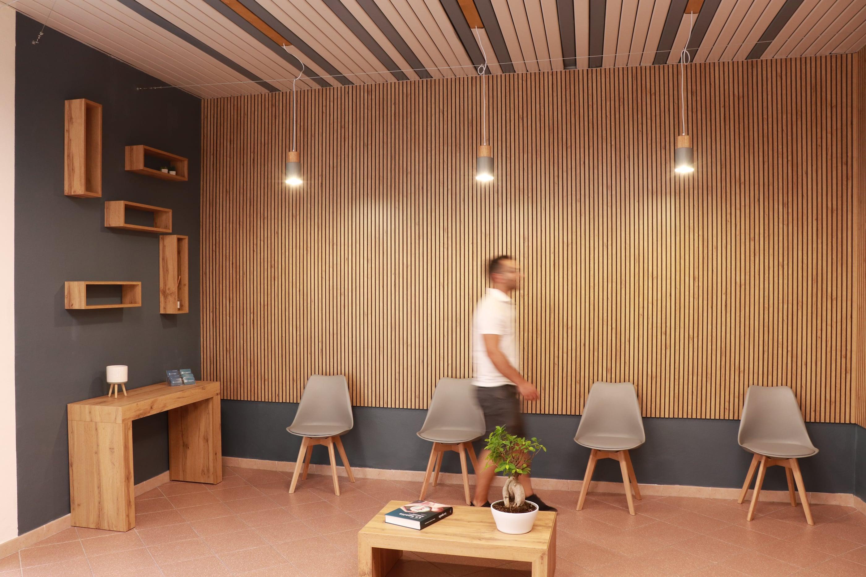Studio F.N., sala d’attesa con sedute, parete a listelli e lampade sospese